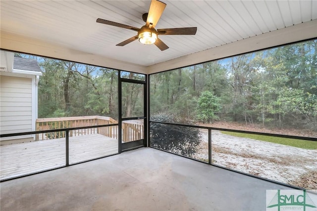 unfurnished sunroom featuring ceiling fan and a view of trees