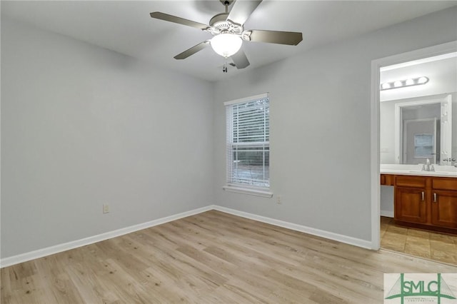 unfurnished bedroom with light wood-style floors, a sink, baseboards, and ensuite bathroom