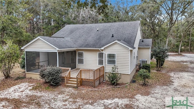 view of front of house featuring a shingled roof, central AC unit, and a sunroom