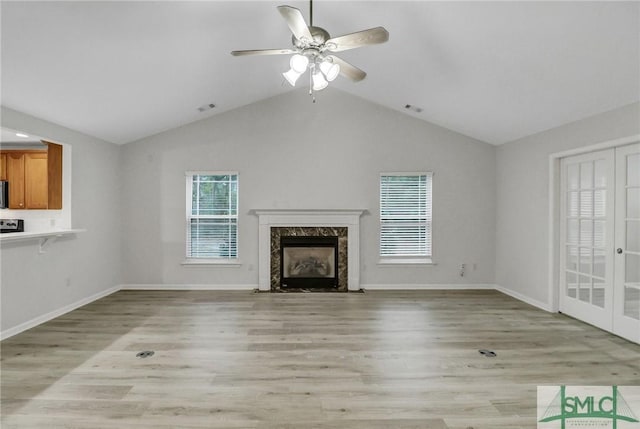 unfurnished living room featuring vaulted ceiling, light wood finished floors, a premium fireplace, and visible vents