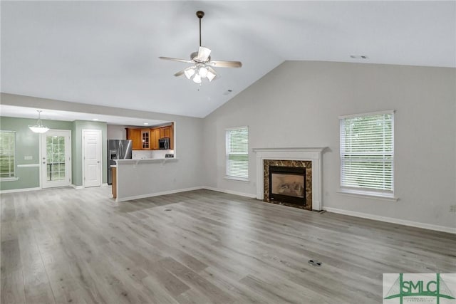 unfurnished living room featuring light wood-style flooring, a fireplace, baseboards, and a ceiling fan