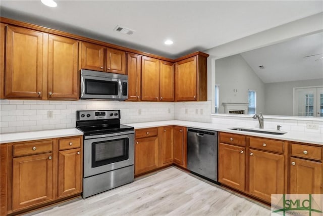 kitchen featuring appliances with stainless steel finishes, brown cabinetry, a sink, and visible vents