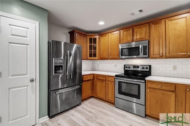 kitchen featuring stainless steel appliances, light countertops, visible vents, and brown cabinets