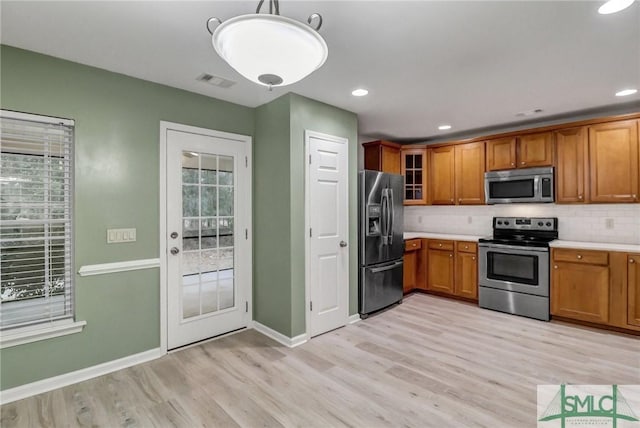 kitchen with stainless steel appliances, tasteful backsplash, visible vents, and brown cabinets