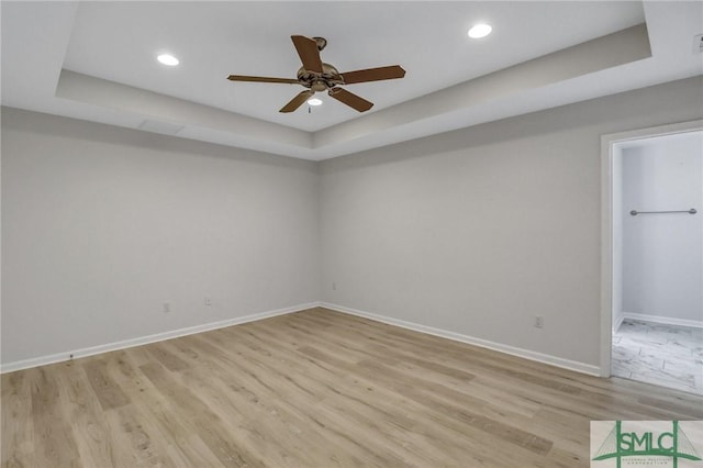 interior space featuring a tray ceiling, baseboards, light wood finished floors, and recessed lighting