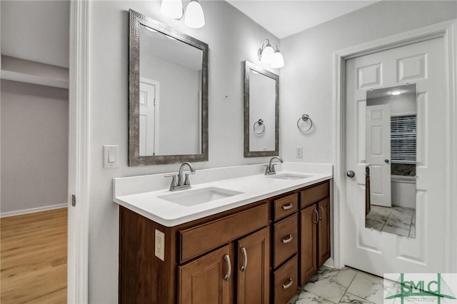 bathroom with marble finish floor, double vanity, and a sink