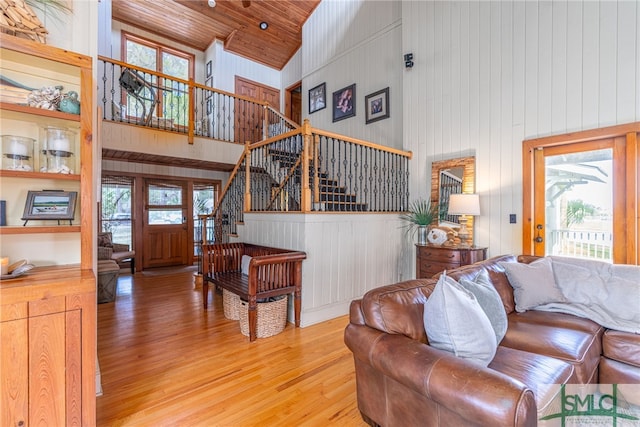 living area with a wealth of natural light, light wood-style flooring, stairway, wood ceiling, and high vaulted ceiling