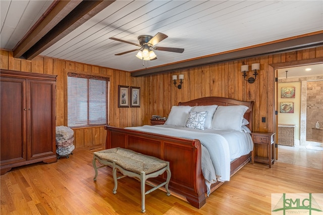 bedroom featuring light wood-style floors, a ceiling fan, beamed ceiling, and wood walls