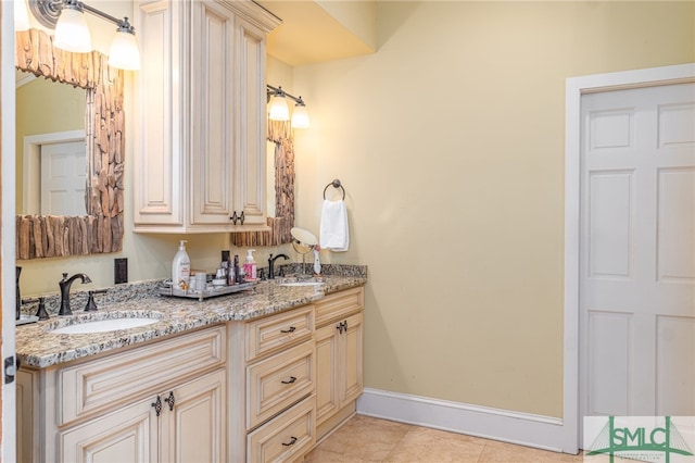 bathroom featuring double vanity, tile patterned floors, a sink, and baseboards