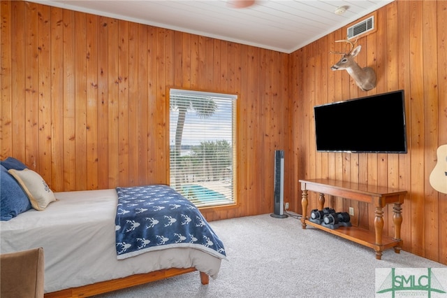 bedroom with carpet floors, wood walls, and visible vents