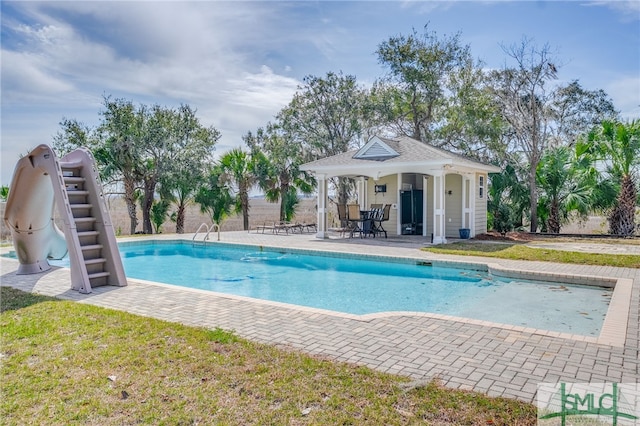 view of pool featuring a fenced in pool, a patio, an outbuilding, a storage structure, and a water slide