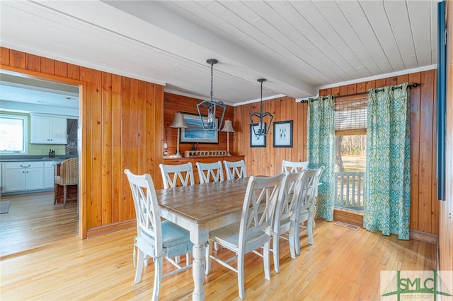 dining room featuring visible vents, light wood-style flooring, and wooden walls