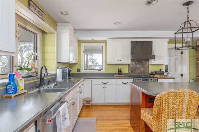 kitchen featuring wall chimney exhaust hood, appliances with stainless steel finishes, a sink, and white cabinetry