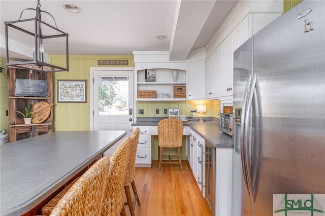 kitchen with light wood-type flooring, dark countertops, white cabinetry, and stainless steel fridge with ice dispenser