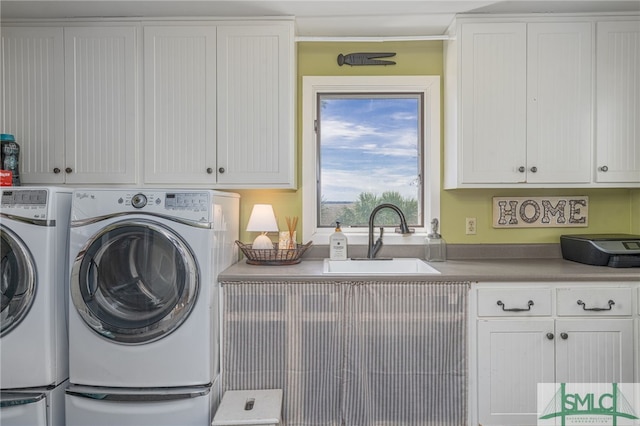 washroom with washing machine and dryer, cabinet space, and a sink