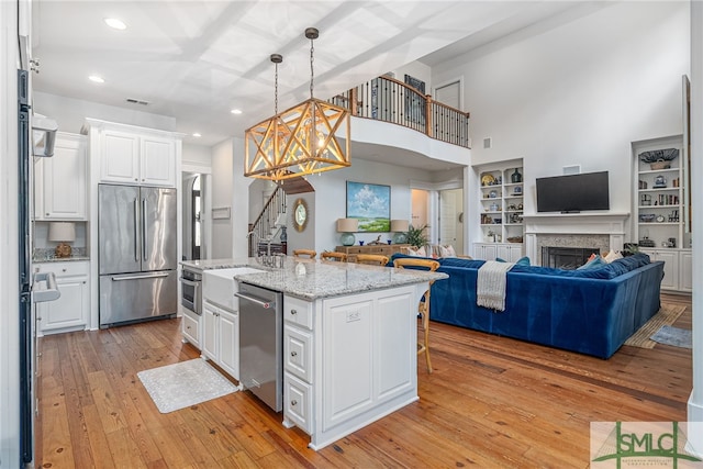 kitchen featuring appliances with stainless steel finishes, open floor plan, white cabinets, and light wood-style flooring