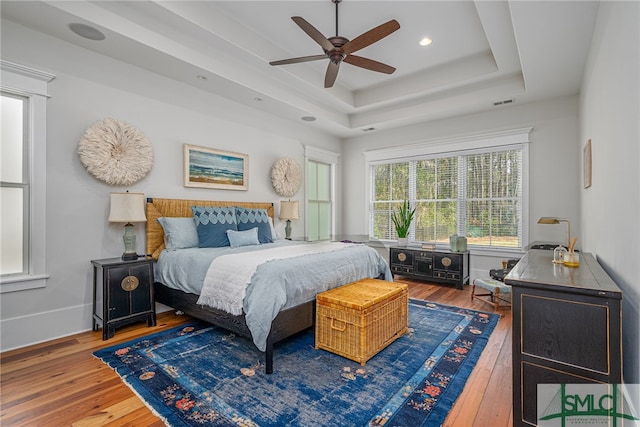 bedroom with a raised ceiling, baseboards, visible vents, and hardwood / wood-style floors