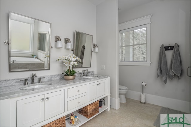 bathroom featuring double vanity, a sink, toilet, and baseboards