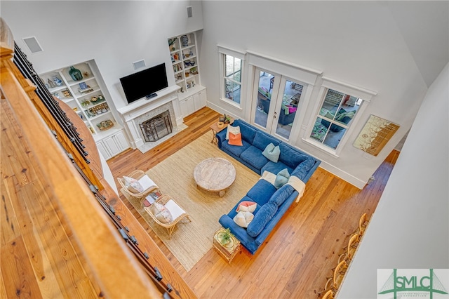 living room with visible vents, a fireplace, a towering ceiling, and wood finished floors