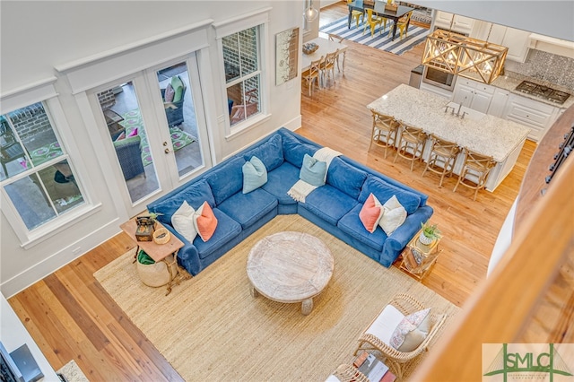 living room featuring a chandelier, french doors, wood finished floors, and baseboards