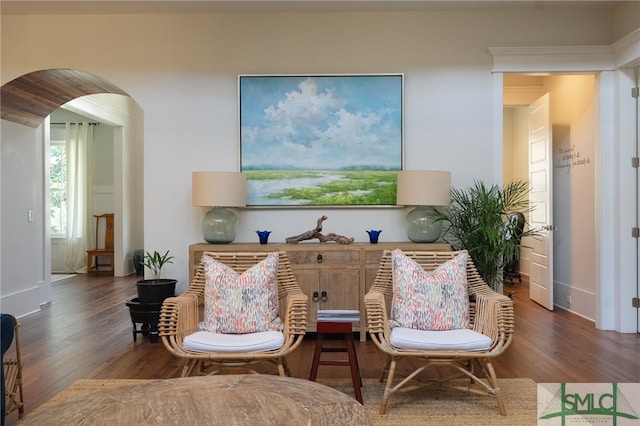 living area featuring arched walkways, baseboards, and wood finished floors