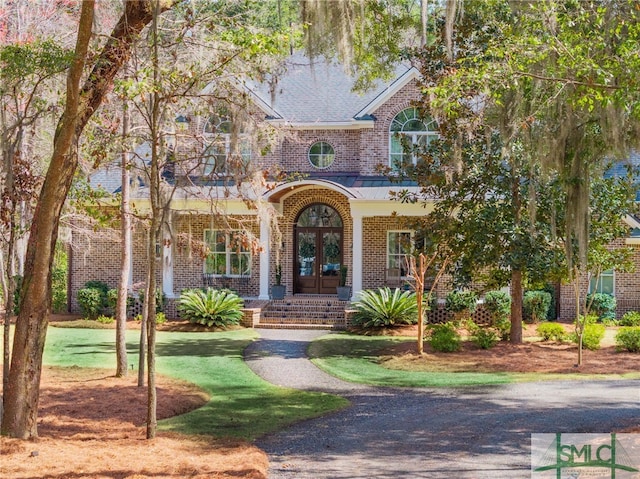 view of front of house with french doors, a front lawn, and brick siding