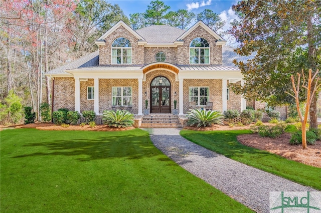 view of front of property featuring french doors, brick siding, a front lawn, and a standing seam roof