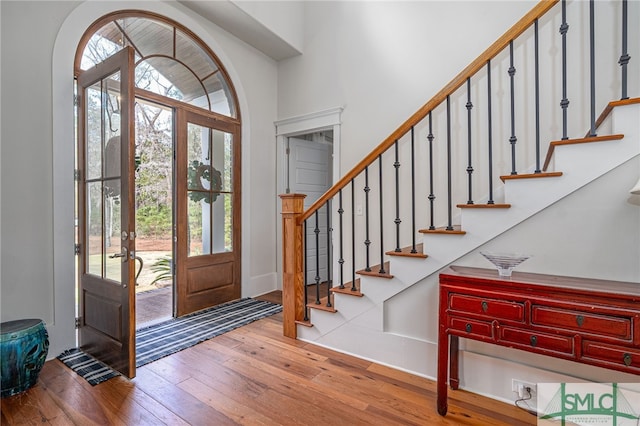 entryway with stairs, hardwood / wood-style floors, and a towering ceiling