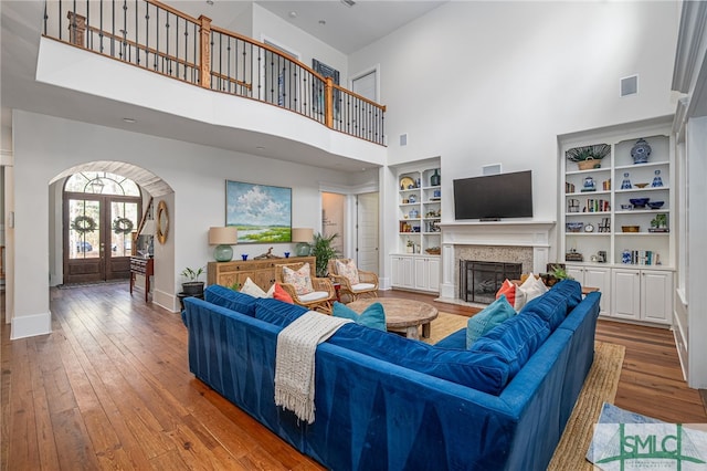 living area with hardwood / wood-style flooring, a fireplace, baseboards, and french doors