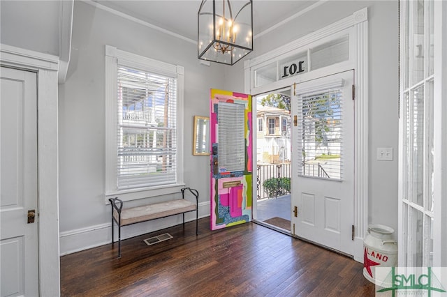 entryway with wood finished floors, visible vents, baseboards, an inviting chandelier, and crown molding