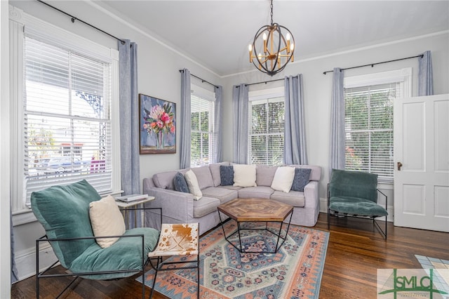 living room featuring a chandelier, crown molding, baseboards, and wood finished floors