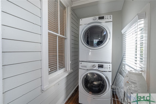 clothes washing area featuring stacked washer and dryer, laundry area, and wooden walls