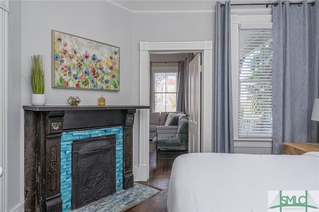 bedroom featuring wood finished floors, a fireplace with flush hearth, and crown molding