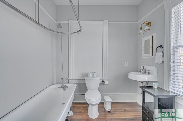 bathroom featuring a sink, a soaking tub, wood finished floors, and a wealth of natural light