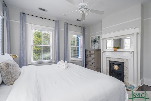 bedroom featuring a tile fireplace, visible vents, and ceiling fan