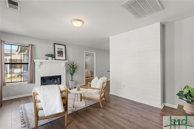 living area with visible vents, a fireplace, and wood finished floors