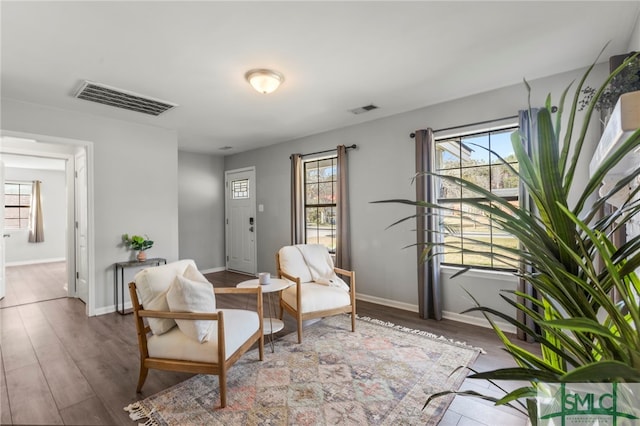 sitting room with wood finished floors, visible vents, and baseboards