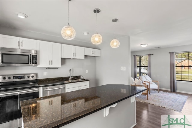 kitchen with stainless steel appliances, white cabinets, a sink, and dark wood-style floors