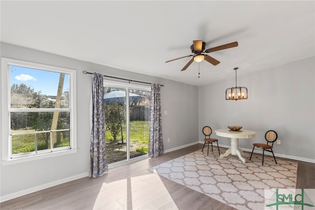 sitting room featuring ceiling fan with notable chandelier, baseboards, and wood finished floors