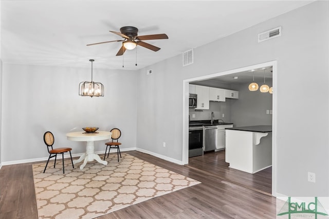 dining room with baseboards, visible vents, dark wood finished floors, and ceiling fan with notable chandelier