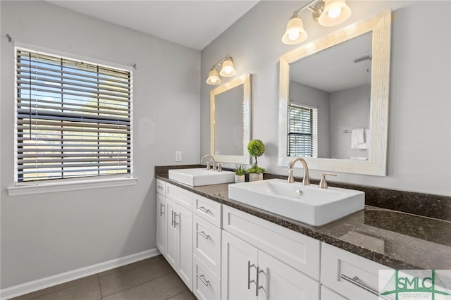 bathroom featuring double vanity, tile patterned flooring, a sink, and baseboards