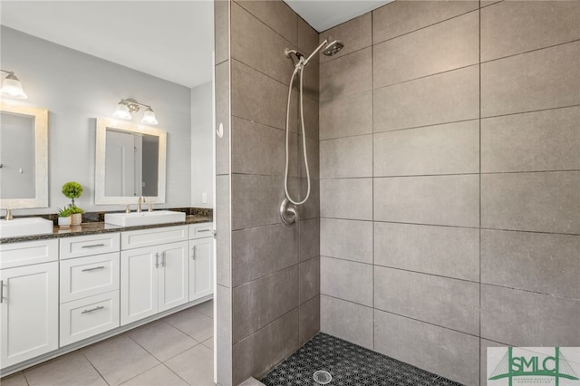 full bathroom with double vanity, tiled shower, a sink, and tile patterned floors