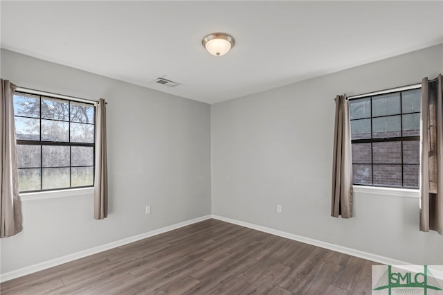 unfurnished room with baseboards, visible vents, and wood finished floors