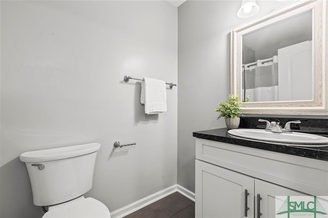 full bath with toilet, tile patterned floors, baseboards, and vanity