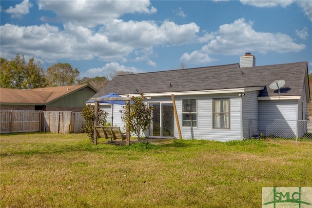 back of house with a fenced backyard, a yard, and a chimney