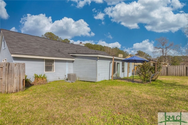 rear view of house featuring a lawn, fence, and central AC