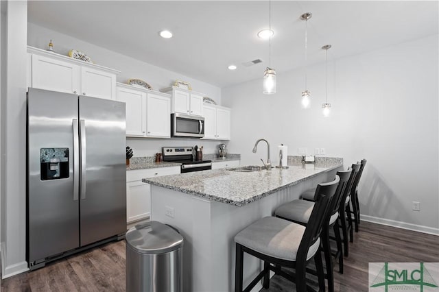 kitchen featuring a peninsula, a sink, white cabinets, a kitchen breakfast bar, and appliances with stainless steel finishes