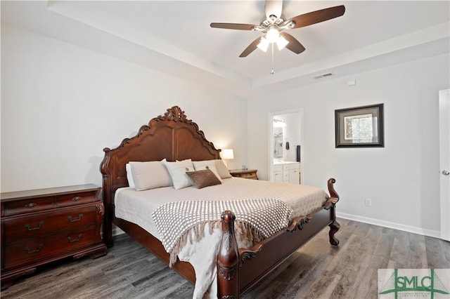 bedroom featuring baseboards, visible vents, connected bathroom, wood finished floors, and a tray ceiling