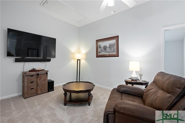 carpeted living area with attic access, a ceiling fan, and baseboards