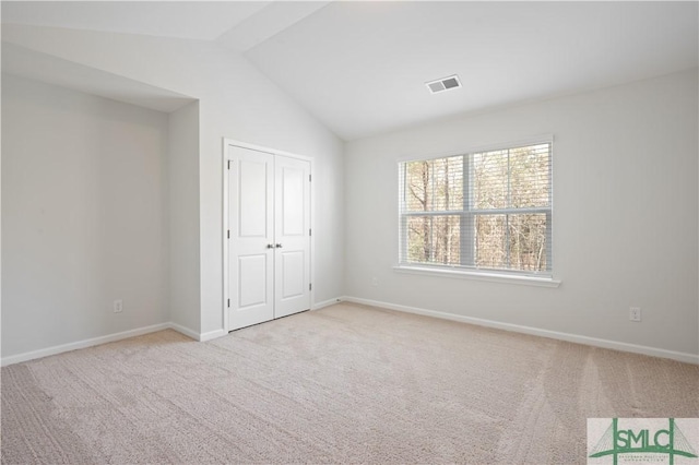 unfurnished bedroom featuring vaulted ceiling, carpet, visible vents, and baseboards